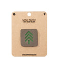 Mini patch with green tree design on a cardboard backing with brand name.