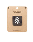 Mini Multicam Black patch with hook and velcro on a cardboard backing, featuring a white logo on a black background.