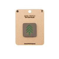 Mini patch with green tree design on a cardboard backing with brand name.