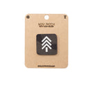 Mini Multicam Black patch with hook and velcro on a cardboard backing, featuring a white logo on a black background.