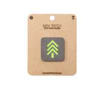 Mini patch with green arrow design on a cardboard backing with 'The Alpinhound' branding.